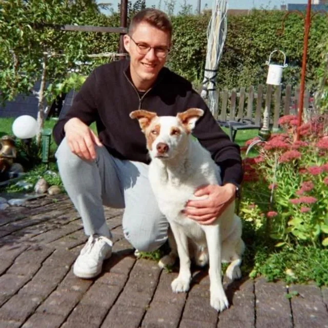 Marvin Kühlmann, in der Hocke neben einem weißen Hund im Garten